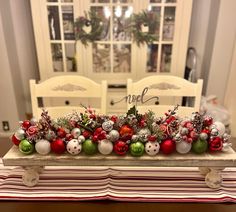 a table topped with lots of ornaments and greenery next to a dining room table