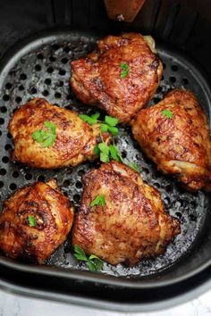 chicken thighs cooking in an air fryer with parsley on the top and green garnish