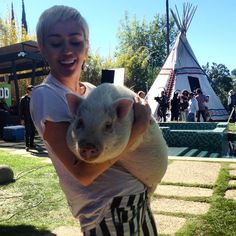 a woman holding a small pig in her arms