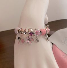 a pink bracelet with charms on it sitting on top of a white mannequin