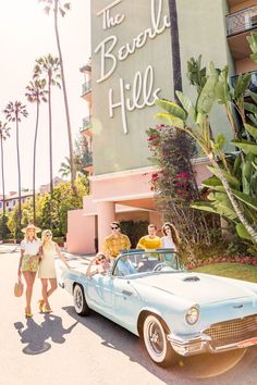 people standing in front of the beverly hills sign with a vintage car parked next to it