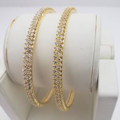 "* Handcrafted Gold Plated 2 Bangle Set. Sold as a set. * Bangles with pretty white CZ stones * High Quality 22 K Gold Plated- 2 Bangle set *2.4 inches= ( 2.25\" diameter of the inner circle) ; 2.6 inches = ( 2.42\" diameter of the inner circle); 2.8inches = (2.54\" diameter of the inner circle) Gorgeous gold-plated bangle/ bracelet best exemplifies the careful craftsmanship done on it -- a specialty at Nemali Jewelry. It has a special tone of elegance attached to it. The intricate handmade desi Dazzling Hoop Jewelry For Wedding, Hoop Bangle For Wedding, Stackable Hoop Jewelry For Wedding, Stackable Hoop Wedding Jewelry, Gold Bridal Sets With Stone Work In Cubic Zirconia, Adjustable Hoop Style Bangle For Wedding, Gold Bridal Sets With American Diamond, Gold Plated Round Bangle For Wedding, Gold Plated Bracelets With Stone Work For Wedding