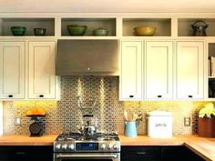 a stove top oven sitting inside of a kitchen next to wooden counter tops and white cabinets