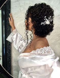 a woman in a white dress is looking at herself in the mirror with her hair up