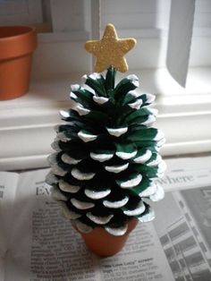 a pine cone christmas tree sitting on top of a paper towel next to a potted plant