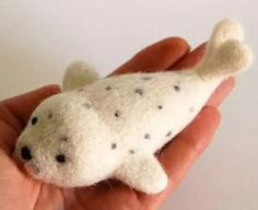 a hand holding a small stuffed animal in it's left hand, with tiny black dots on the fur