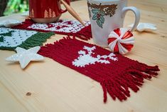 two coffee mugs are sitting on a table next to knitted christmas scarves