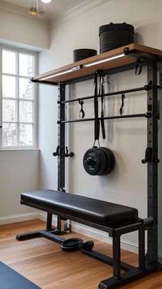 a gym room with a bench, weights and barbells hanging on the wall