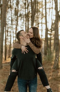 a man and woman hug each other in the middle of a wooded area with trees