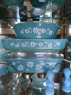 blue dishes are stacked on top of each other in front of glass shelves filled with plates and bowls