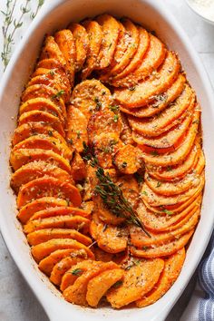 a casserole dish filled with sliced sweet potatoes