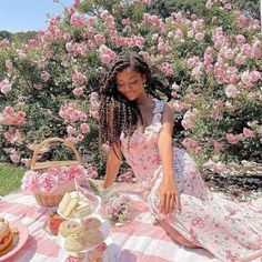 a woman sitting at a picnic table in front of pink roses and teacups