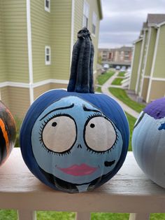 three painted pumpkins sitting on top of a wooden bench