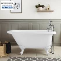 a white bath tub sitting in a bathroom next to a rug and framed pictures on the wall