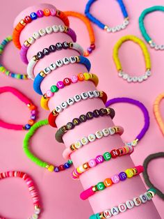 a stack of bracelets sitting on top of a pink surface next to each other