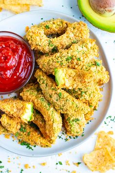 fried chicken sticks with ketchup and avocado on a plate next to crackers