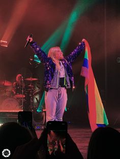 a woman standing on top of a stage with her arms in the air and holding a microphone