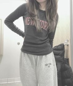 a woman standing in front of a mirror wearing sweat pants and a new york shirt