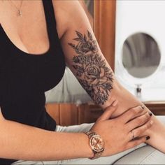 a woman with a flower tattoo on her arm and wrist sitting in front of a mirror