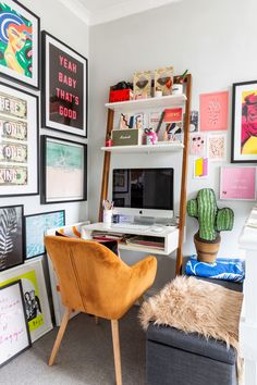 a desk with a computer on top of it next to a chair and bookshelf