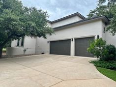 a white house with two garages and trees