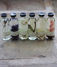 six bottles with different types of flowers in them sitting on a stone surface next to each other