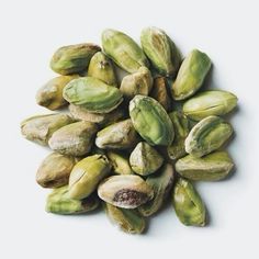 pistachios on a white surface with no one in the photo looking at them