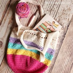 a crocheted bag sitting on top of a wooden floor next to yarn and scissors