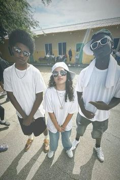 three young people standing next to each other in front of a building with sunglasses on