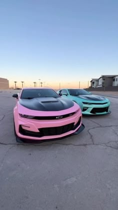 two pink and blue cars are parked in a parking lot with no one around them