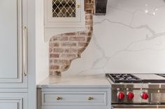 a kitchen with an oven, stove and cabinets in white marble counter tops that have red knobs on them