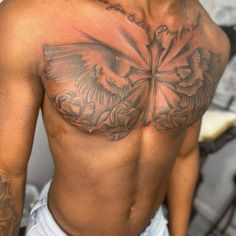 a man with tattoos on his chest has a cross and wings tattoo on his chest