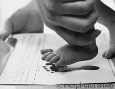 a black and white photo of a baby's foot on top of a paper