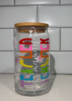 a glass jar with colorful letters painted on it