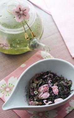 a white bowl filled with food next to a tea pot and pink napkin on top of a table