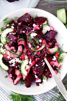 a white bowl filled with beets, cucumbers and feta cheese on top