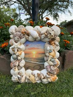 a photo frame made out of seashells in the grass