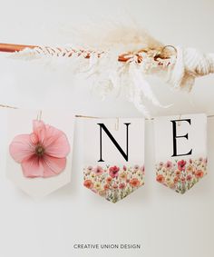 some cards hanging on a clothes line with the letters n e and flowers in them