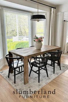 a dining room table with four chairs and a vase on top of it in front of a window