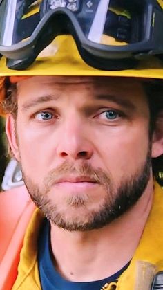 a man wearing a yellow fireman's helmet and goggles