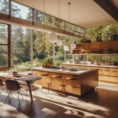 a kitchen with lots of windows and wooden furniture in the center, surrounded by trees