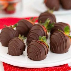 chocolate covered strawberries sit on a white plate