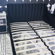 a bed with black and white bedspread next to a night stand in a bedroom