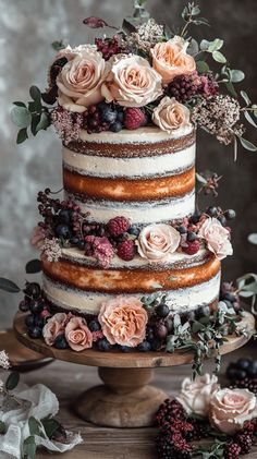 a multi layer cake with flowers and berries on top