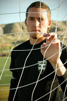 a man standing in front of a soccer net with his finger pointing at the net