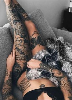 a woman laying on top of a couch covered in lots of tattooed arms and legs