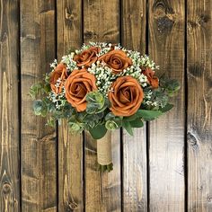 a bouquet of orange roses sitting on top of a wooden table