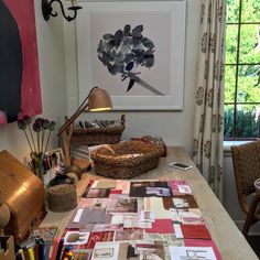 a wooden table topped with lots of crafting supplies next to a painting on the wall