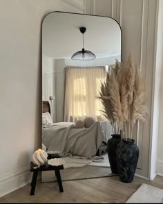 a mirror sitting on top of a wooden floor next to a vase filled with flowers