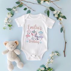 This specially designed unicorn themed 1st birthday bodysuit can be personalized in pastel tones. It is compatible with the most popular themes in the USA with the text 'Emilia's 1st Birthday'. Unicorn themed 1st birthday bodysuit is one of the most preferred birthday concepts for girls in the USA. This design, decorated with unicorns and stars in pastel colors, offers a simple yet striking aesthetic. It can be personalized with the phrase 'Emilia's 1st Birthday' in a handwritten style. It is a Unicorn 1st Birthday, Birthday Bodysuit, Unicorn Themed Birthday Party, Birthday Souvenir, First Birthday Outfit, Unicorn Theme, First Birthday Outfits, Gender Neutral Baby, Birthday Outfit